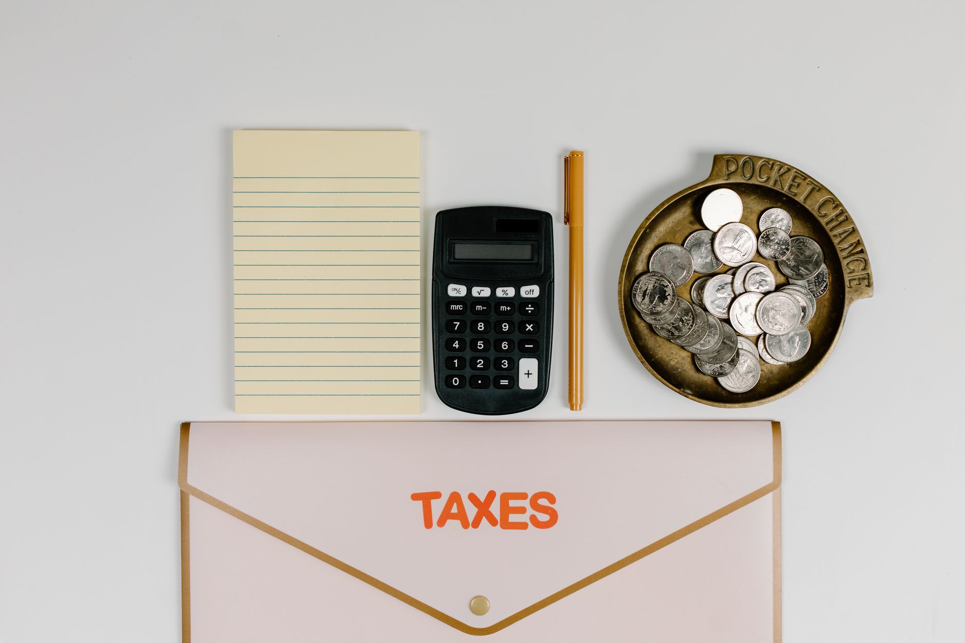 Calculator and a small stack of coins on a white background