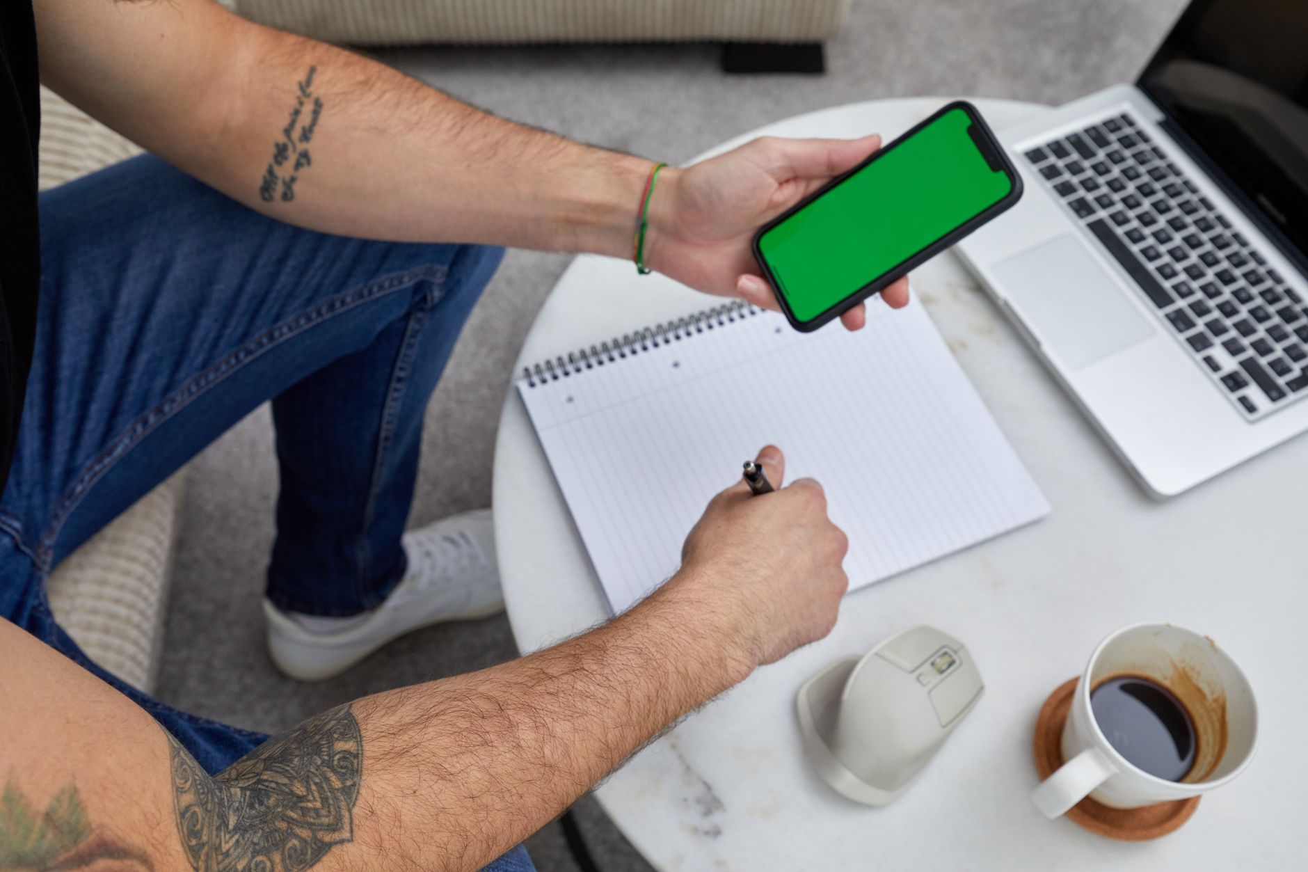 Person drafting notes beside a phone on a tripod