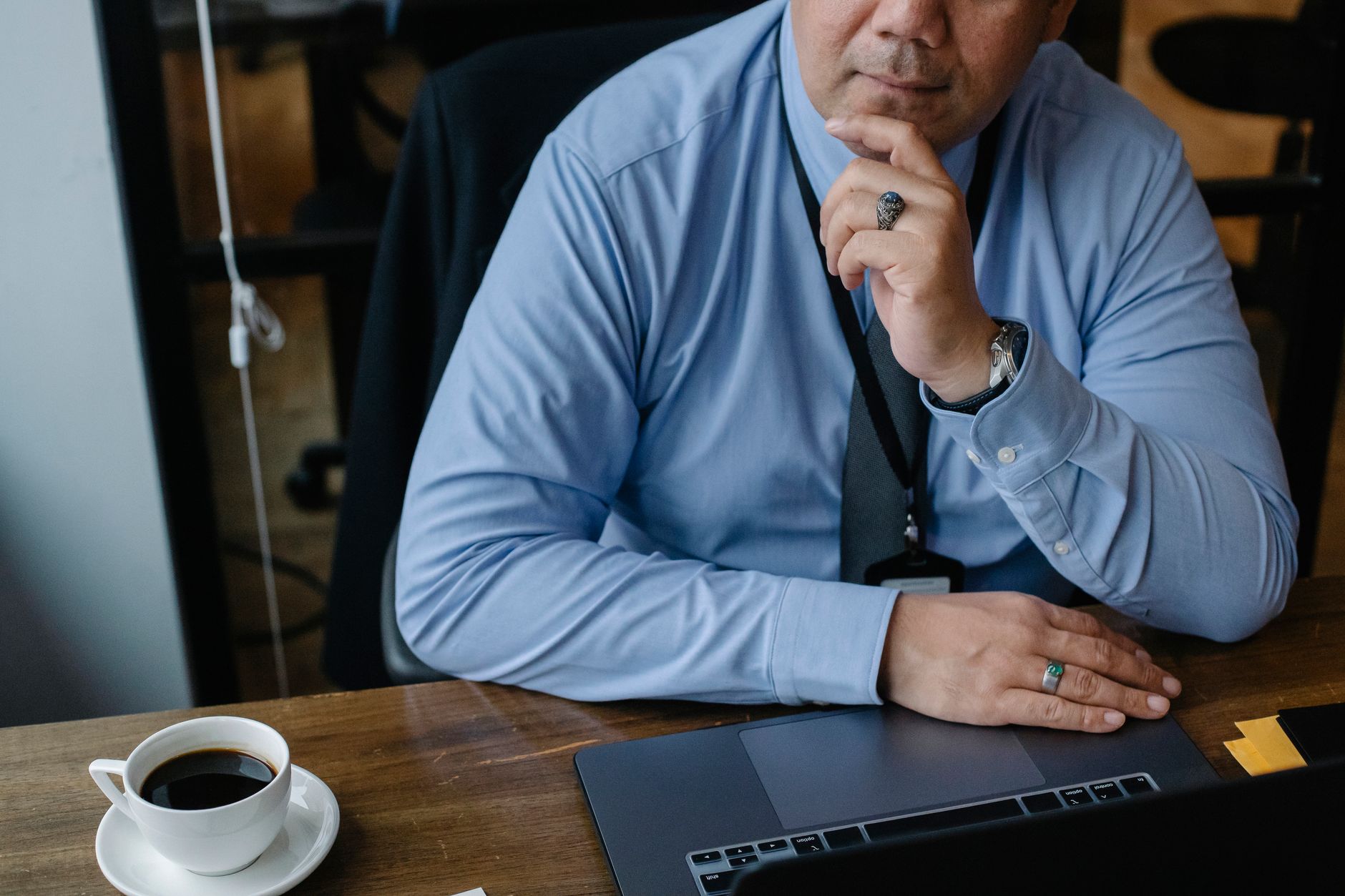 Small business owner at a kitchen table thinking while looking at a laptop