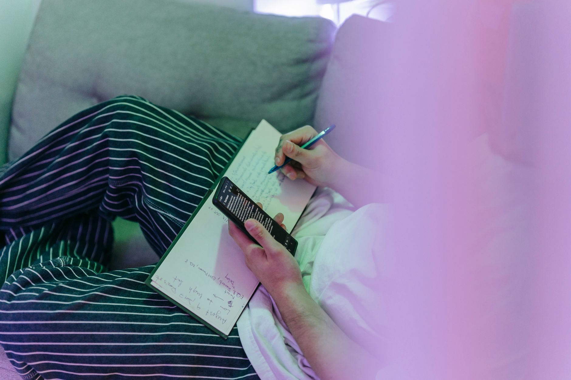 Person watching short vertical videos on a phone and taking notes