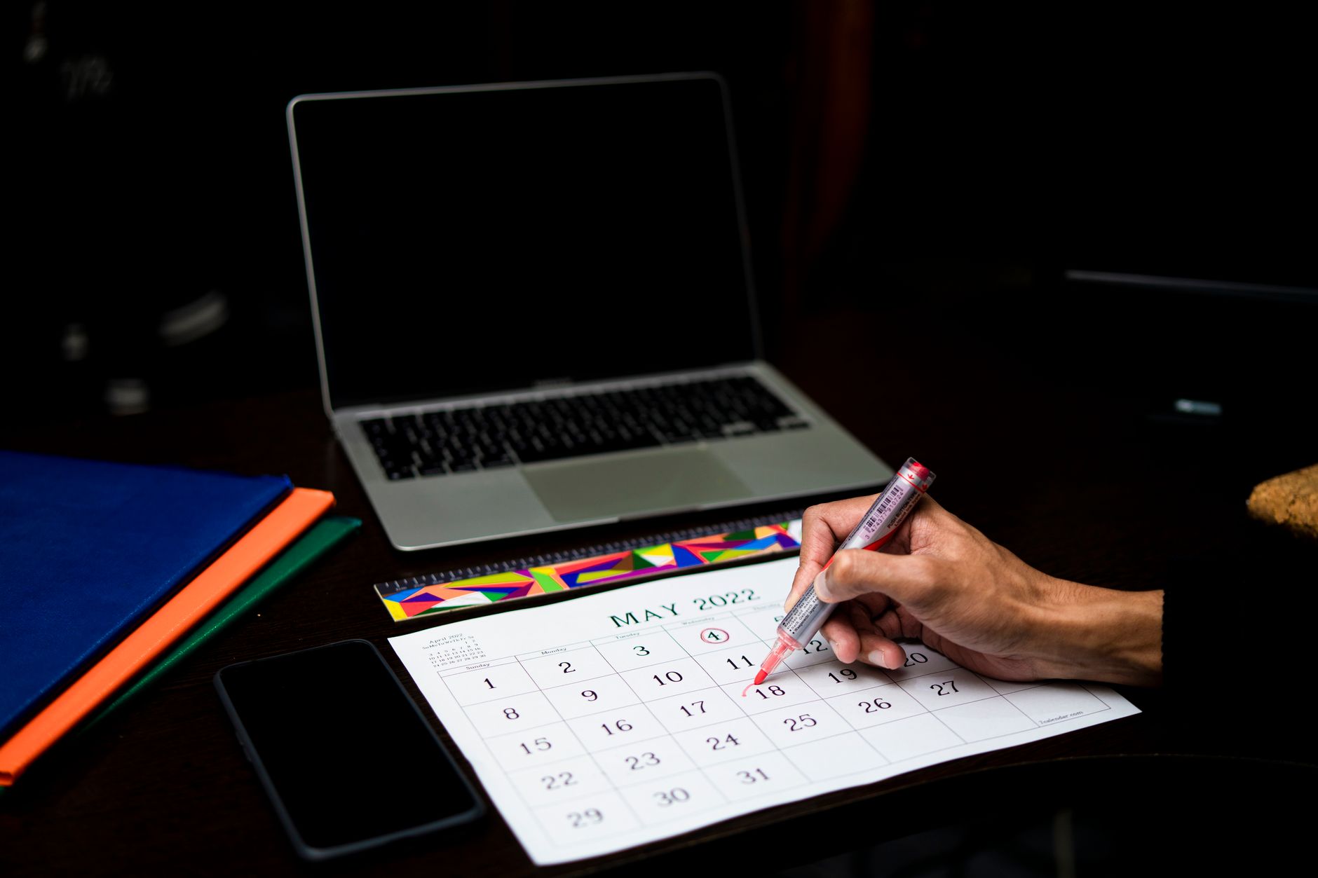 A person plans a weekly posting schedule with a phone and a paper planner.