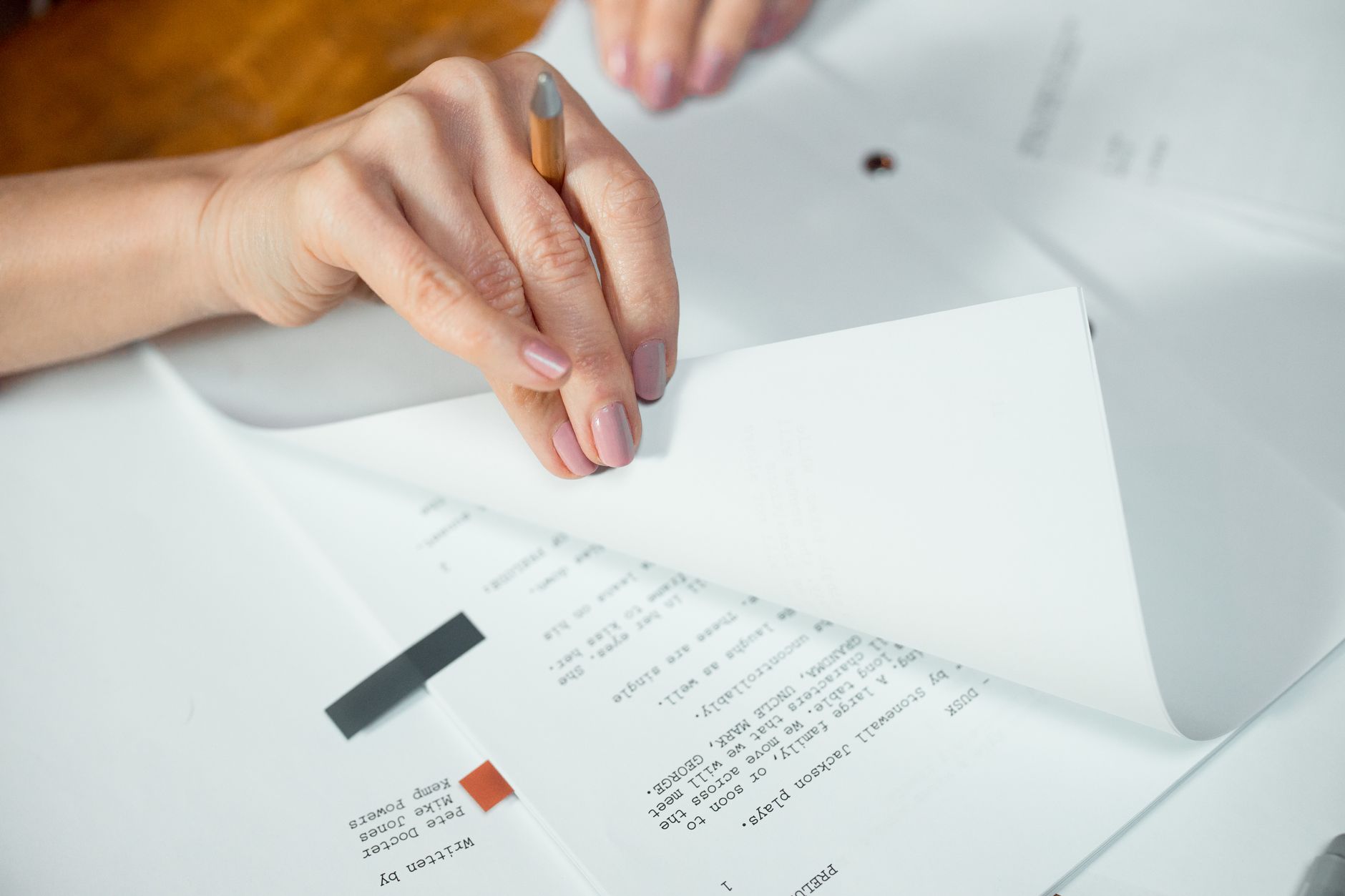 A creator rewrites a script by hand next to a laptop.