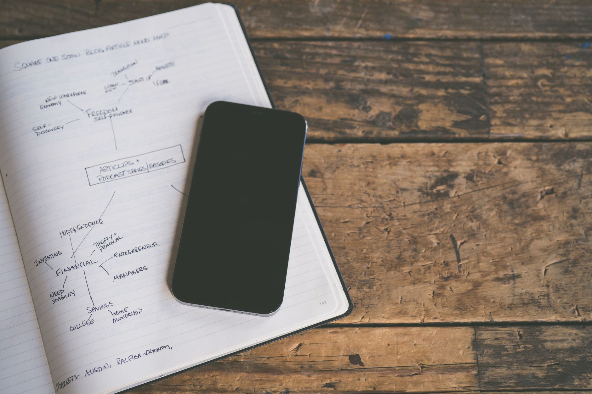 Someone scrolls short videos on a phone and takes research notes.