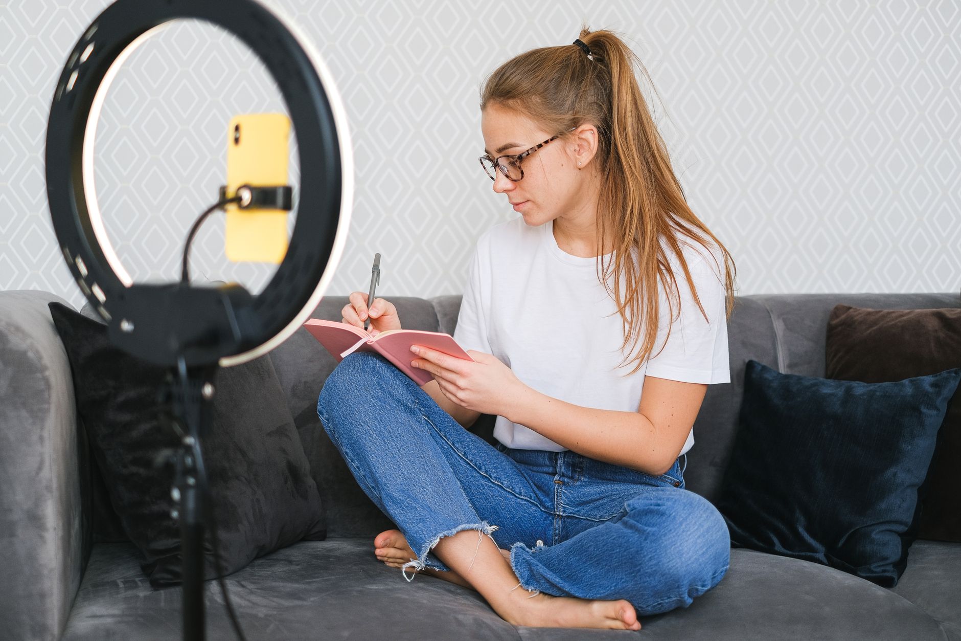 A creator writing in a notebook next to a ring light.