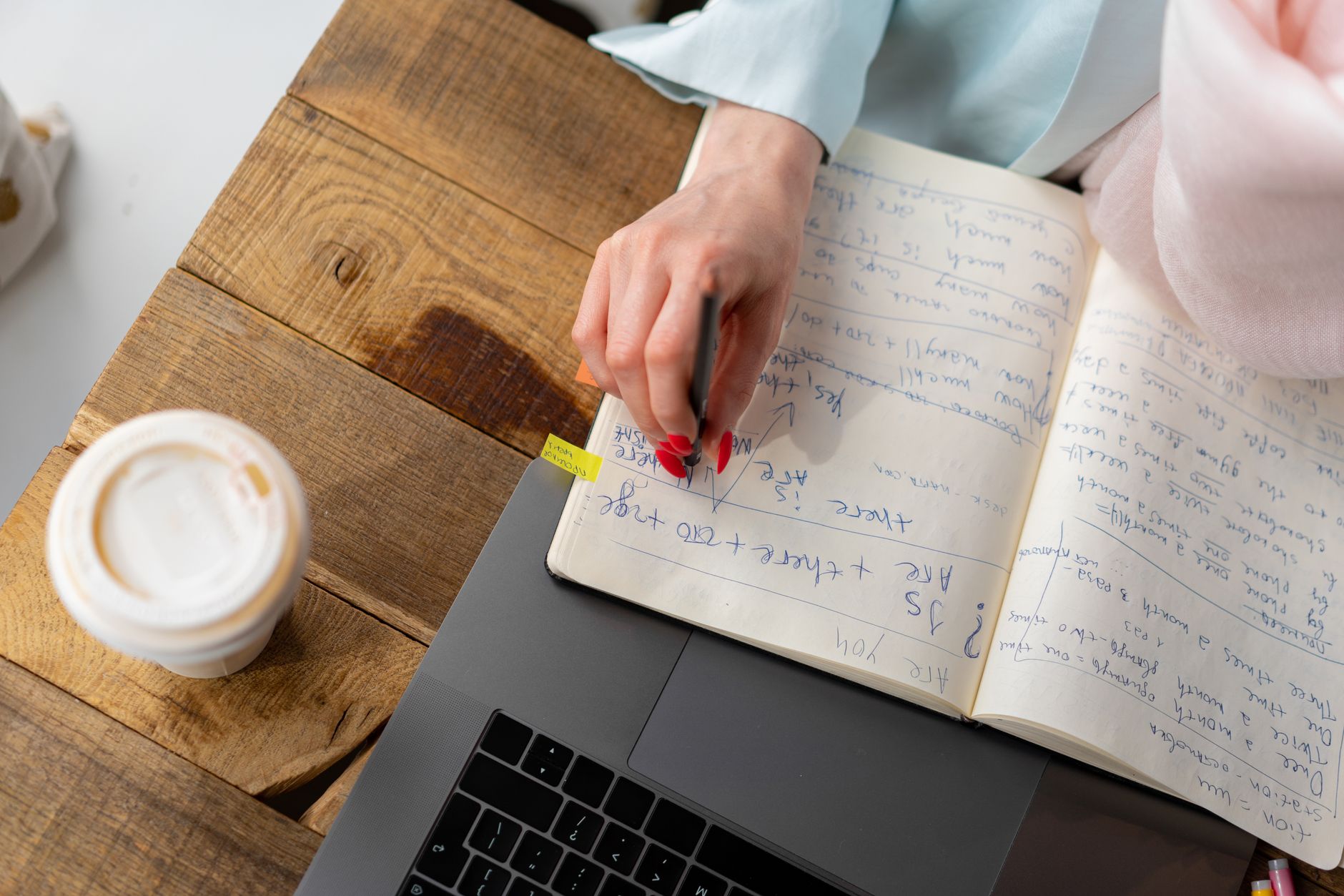 Overhead view of a notebook with rewritten drafts beside coffee